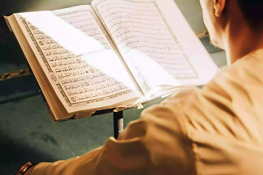 An over-the-shoulder view of a person reading Arabic text from a Mushaf on a stand, contemplating how many hours to read the Quran daily.